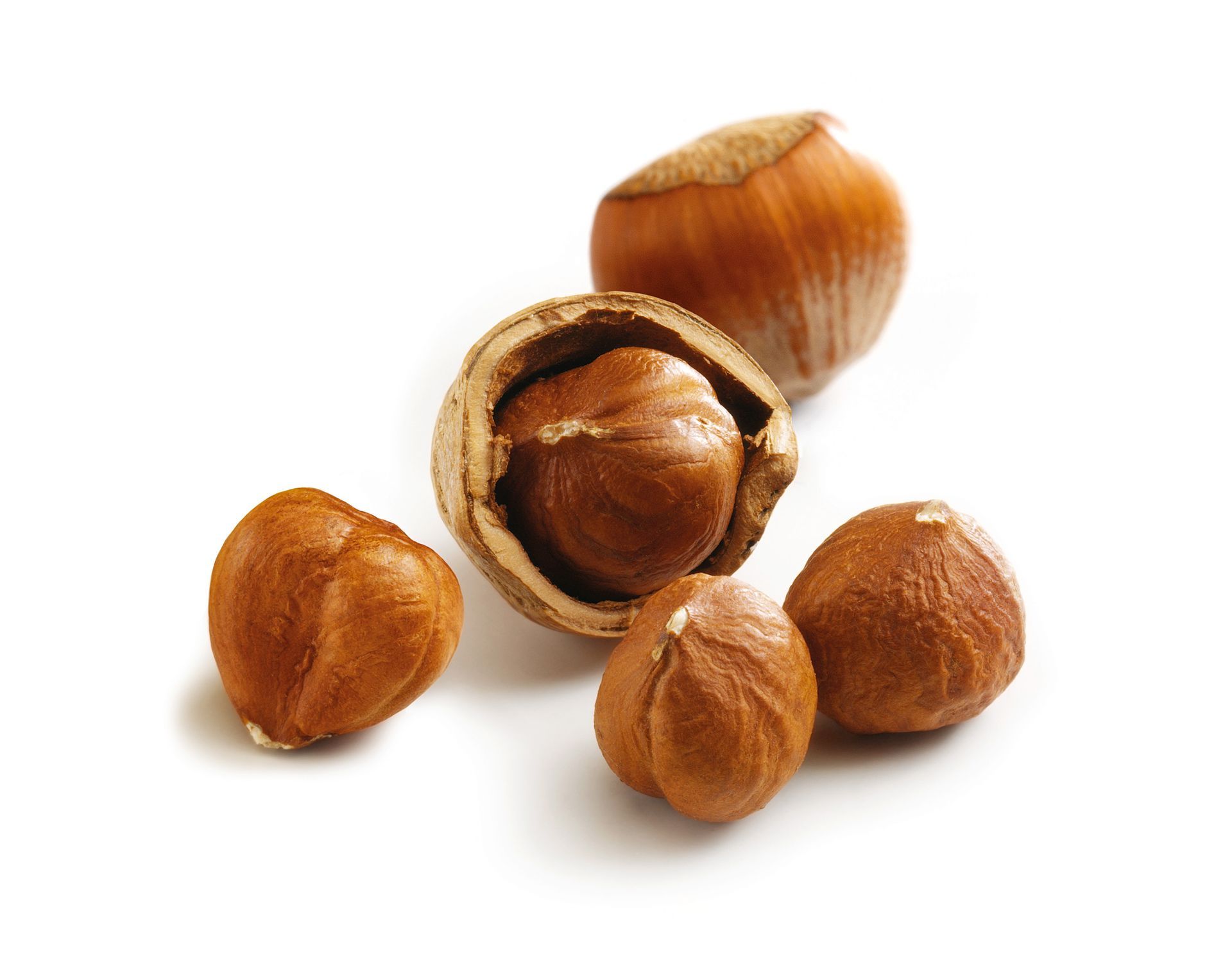 Several hazelnuts, one cracked open showing the nut inside, on a white background
