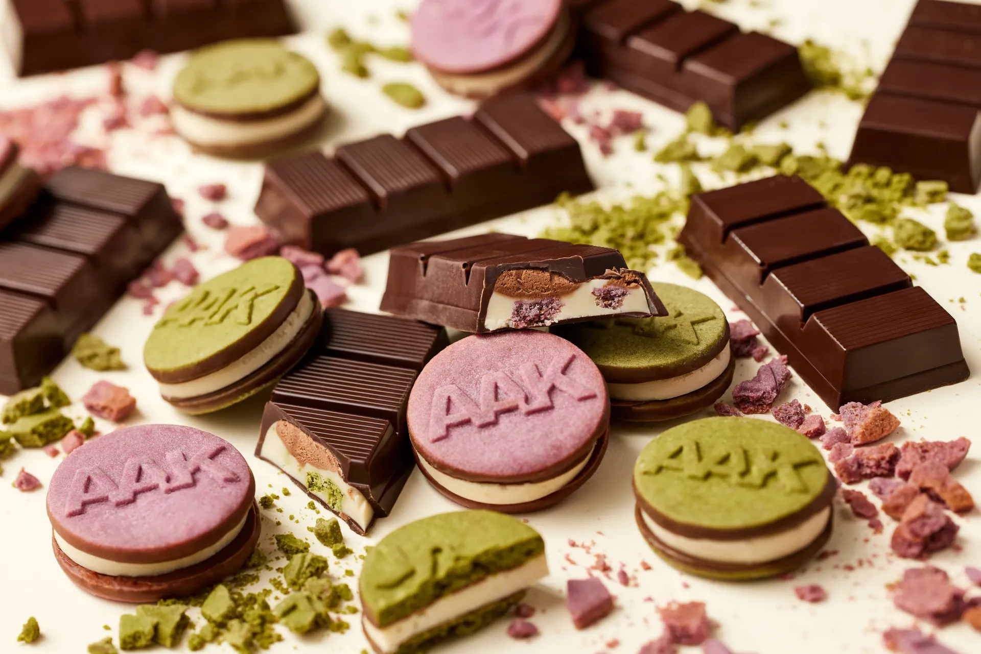 Assorted pink and green macarons and chocolate squares scattered on a dessert platter