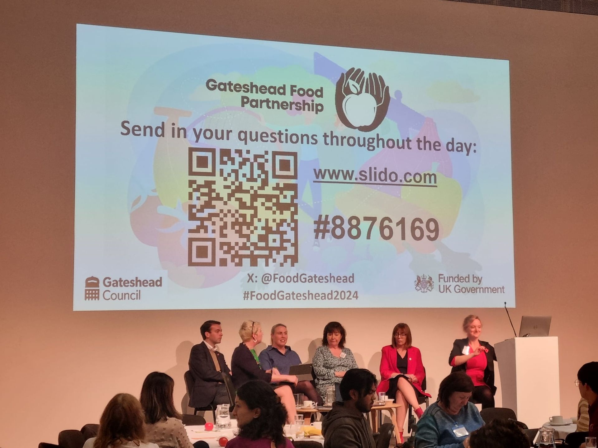 A group of people sitting in front of a screen that says