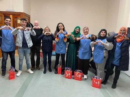 A group of people are standing in a room making heart shapes with their hands.