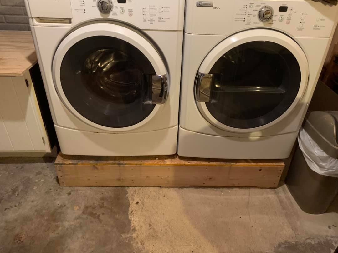 a washer and dryer are sitting on a wooden shelf in a laundry room .