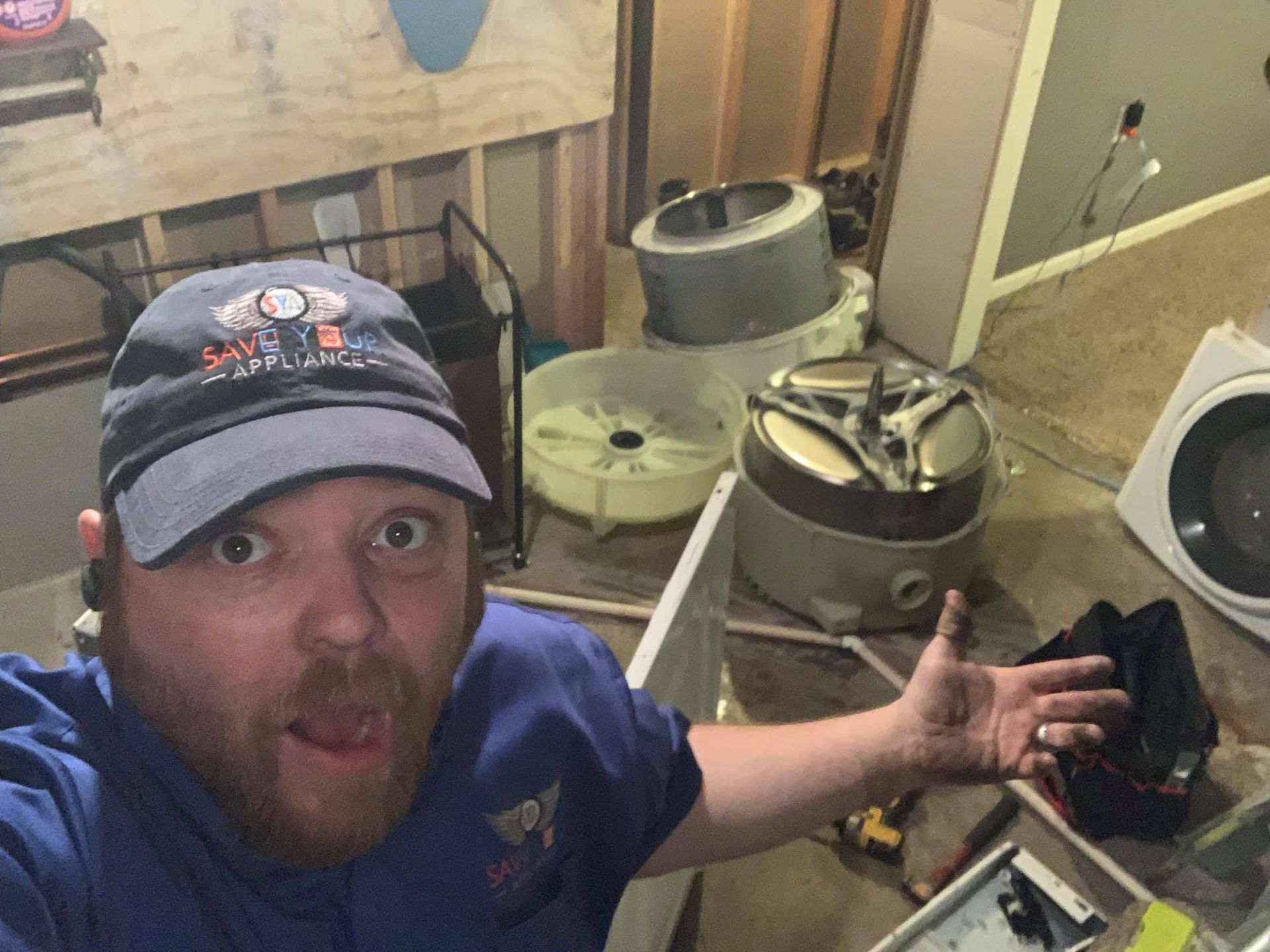 a man is taking a selfie in a room with a washer and dryer .