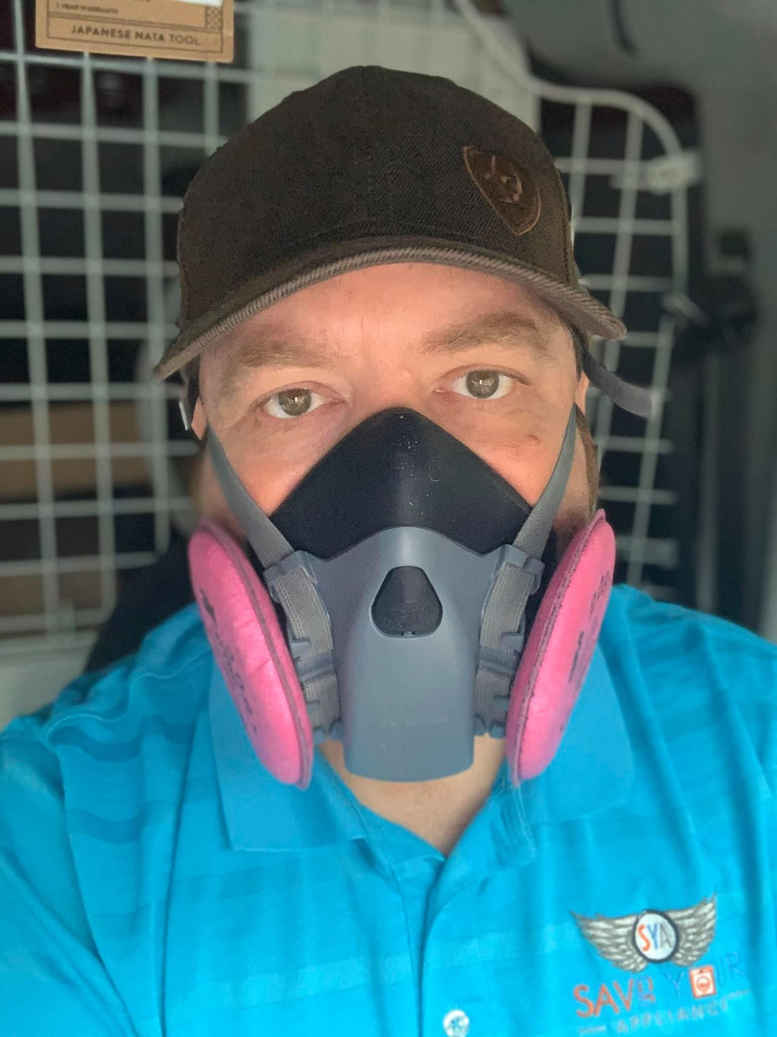 a man wearing a mask and a hat is taking a selfie .
