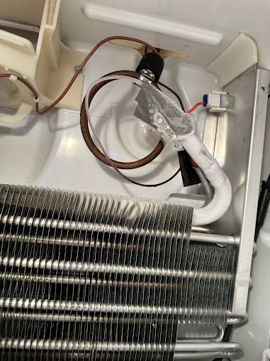 the inside of a refrigerator with a lot of wires coming out of it .