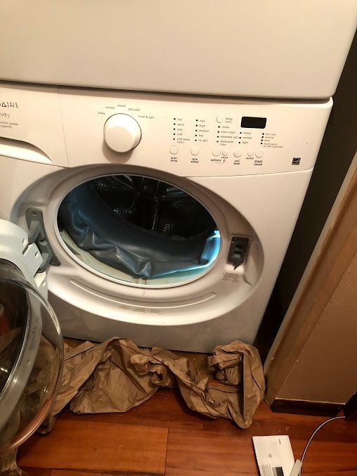 a washer and dryer are stacked on top of each other on a wooden floor .