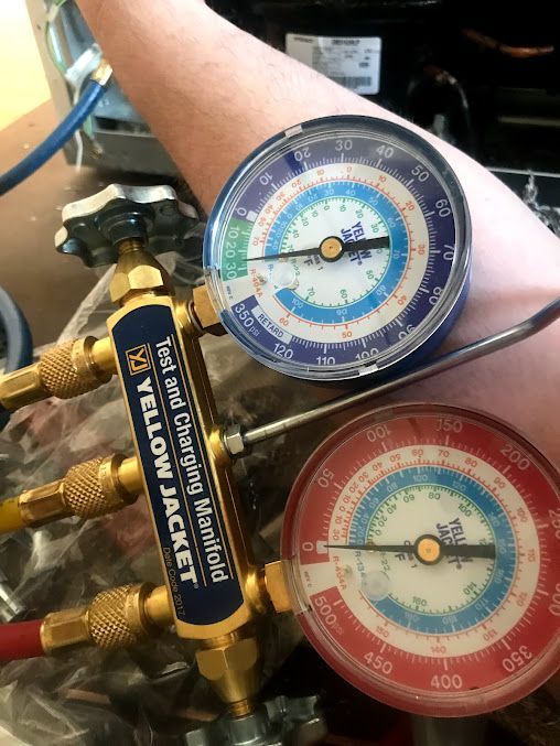 a person is holding a yellow jacket gauge on their arm .