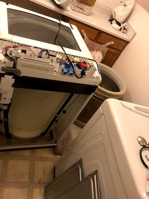 a washing machine is being repaired in a laundry room
