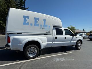 White pickup truck with a large, boxy camper shell; 