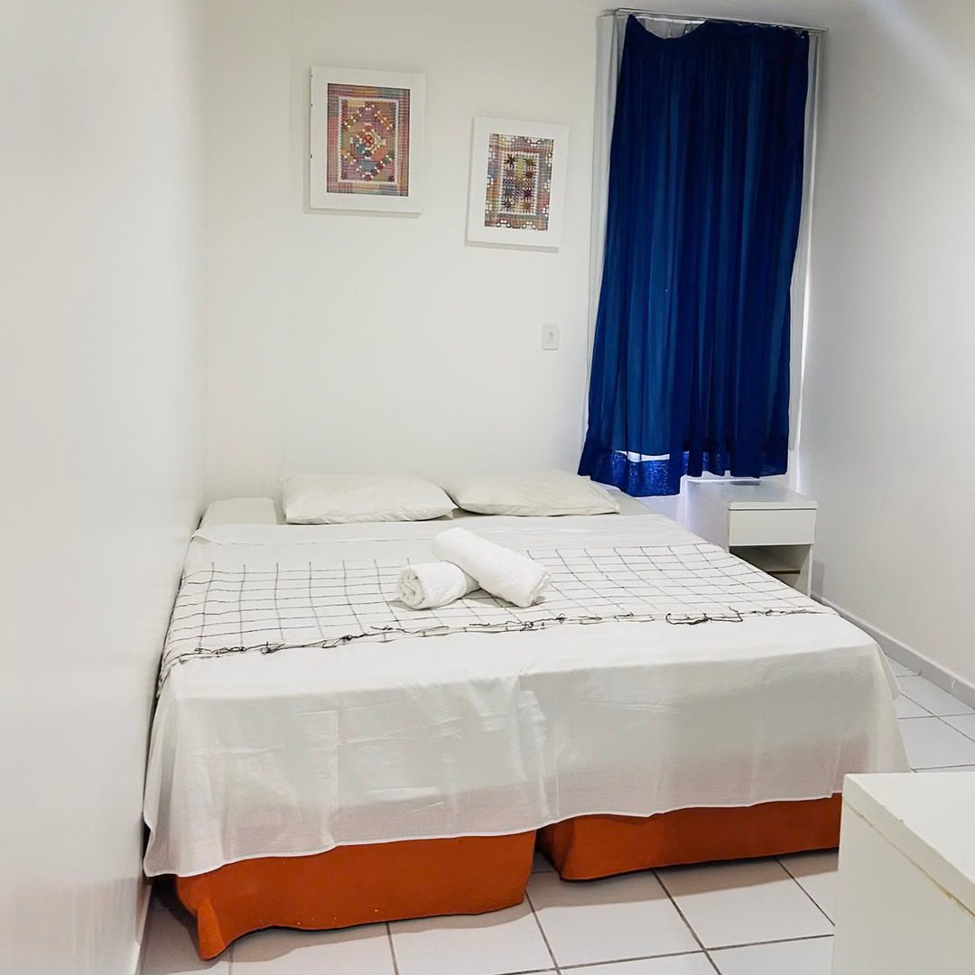 Um quarto com uma cama e uma janela com cortinas azuis