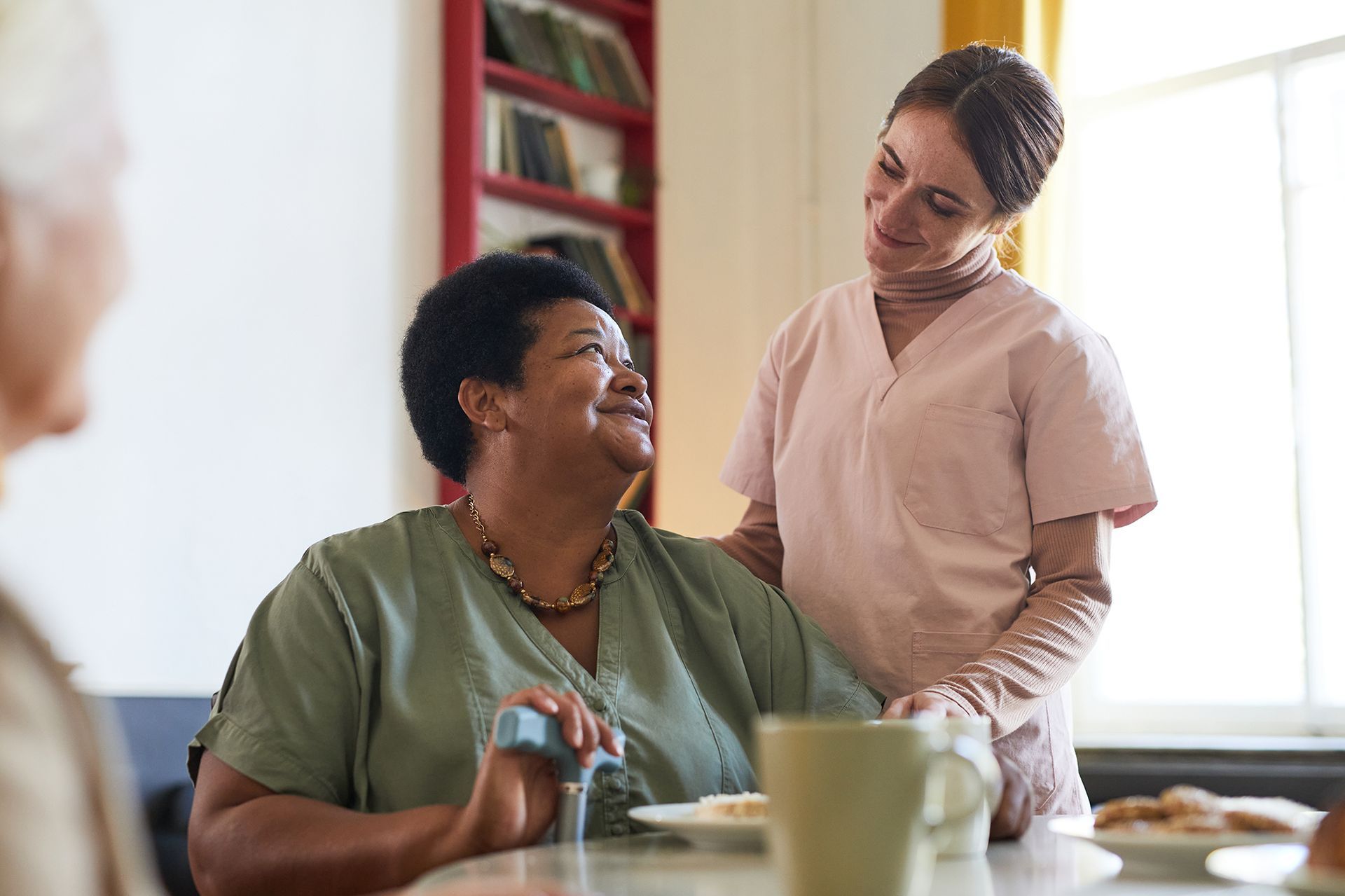A woman is sitting at a table with a nurse standing next to her