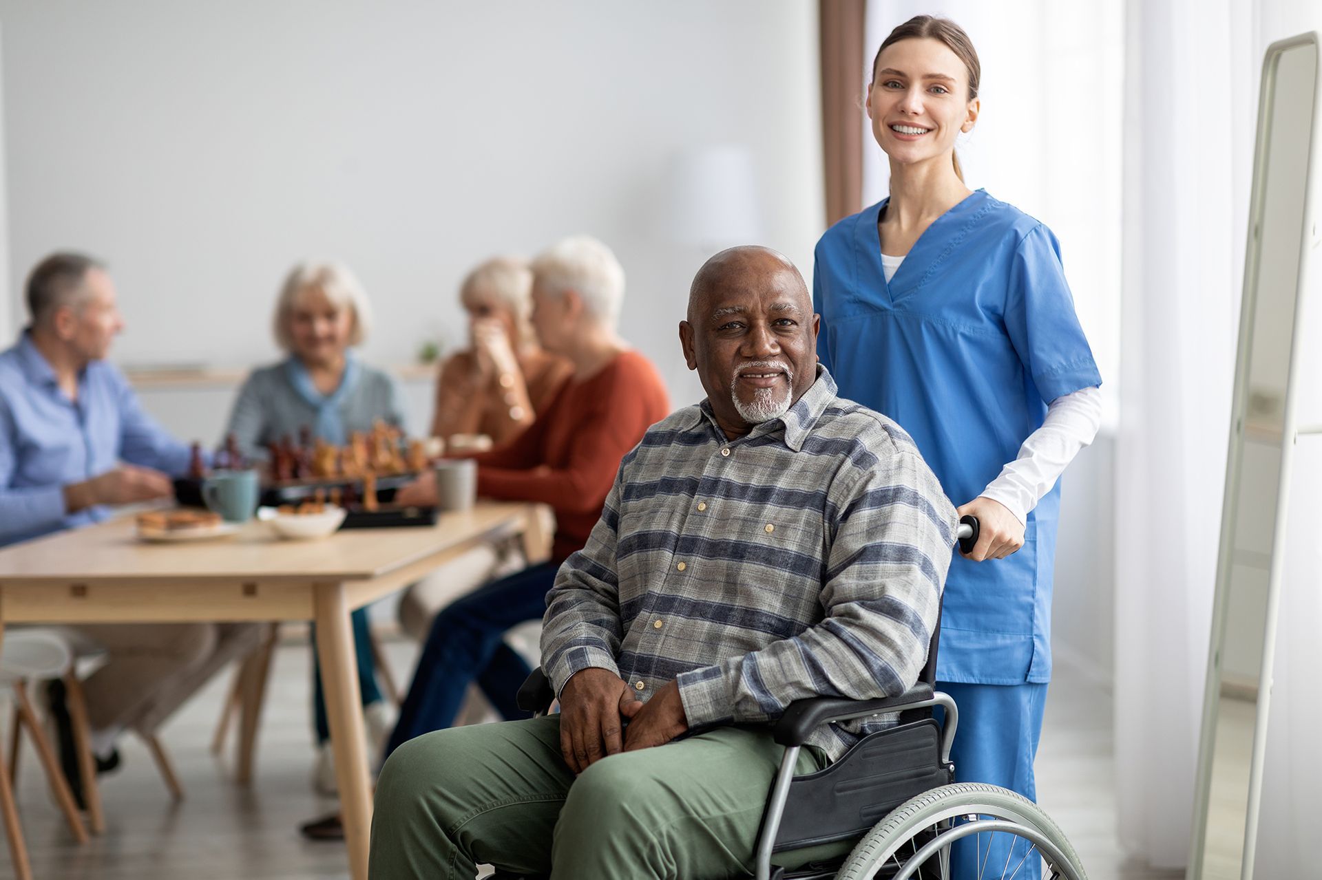 A nurse is standing next to an elderly man in a wheelchair