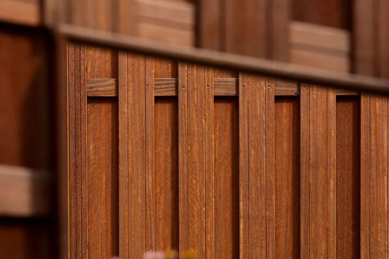 Wooden slatted fence with vertical panels and brown wood grain close-up