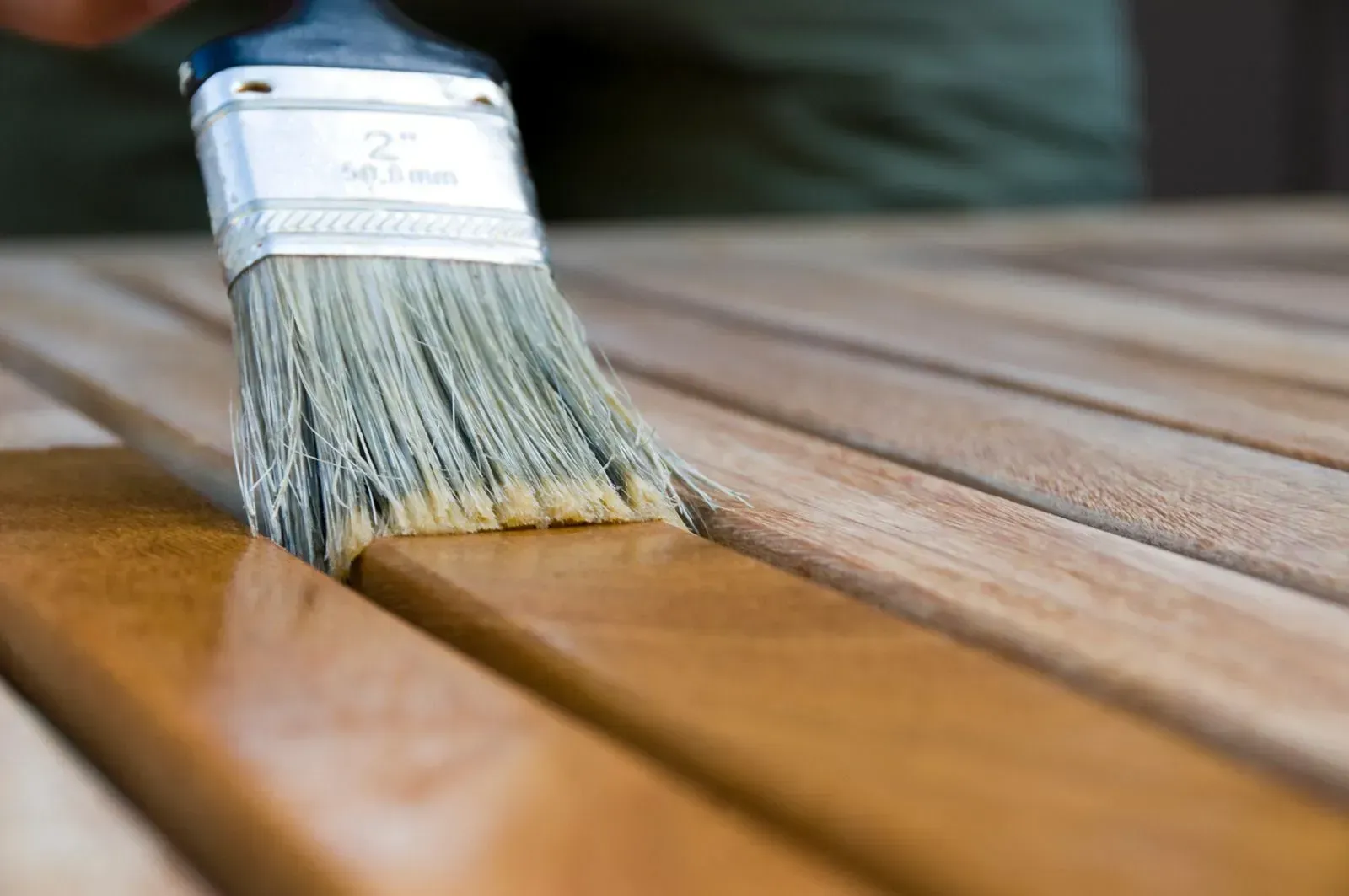 Paintbrush applying varnish to a wooden surface