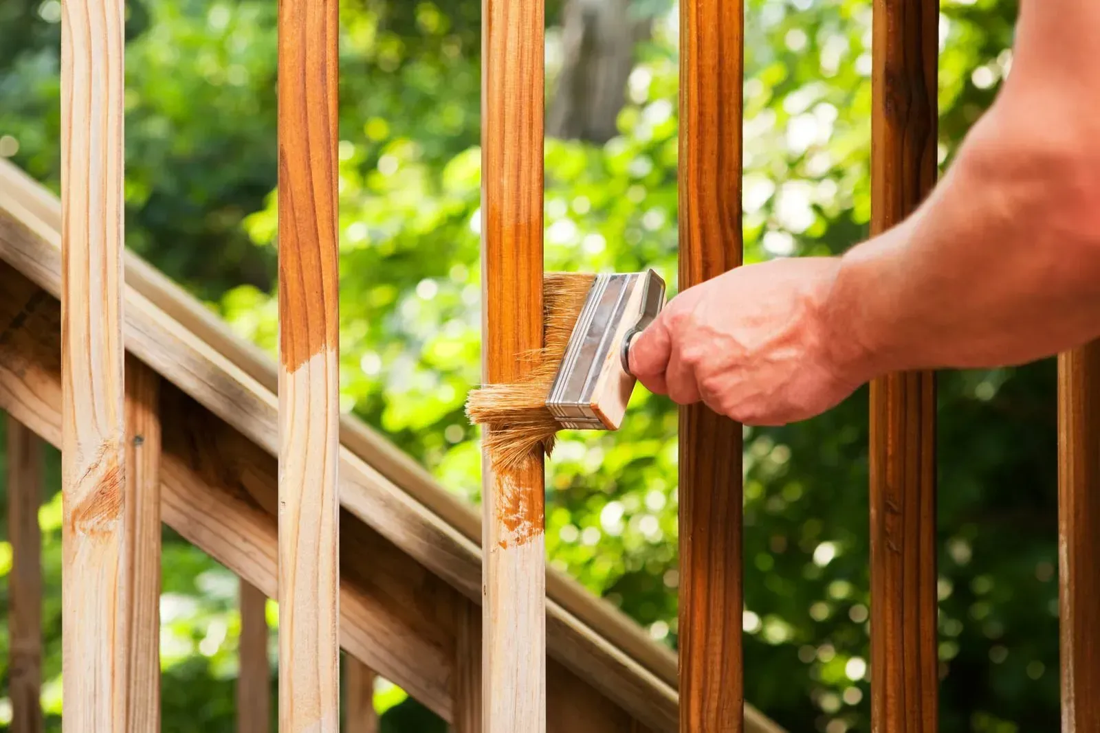 Hand using a hammer to remove a nail from a wooden deck railing