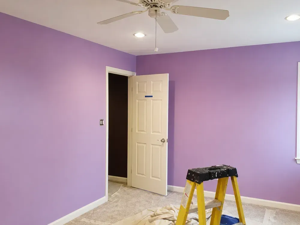 Purple room with white trim, open door, and yellow step stool on unfinished floor.