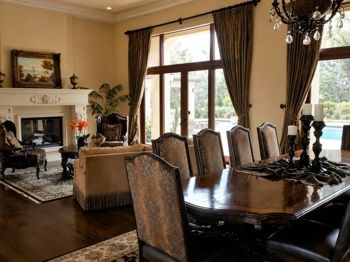 Elegant dining room with dark wood table, upholstered chairs, chandelier, fireplace, and tall windows