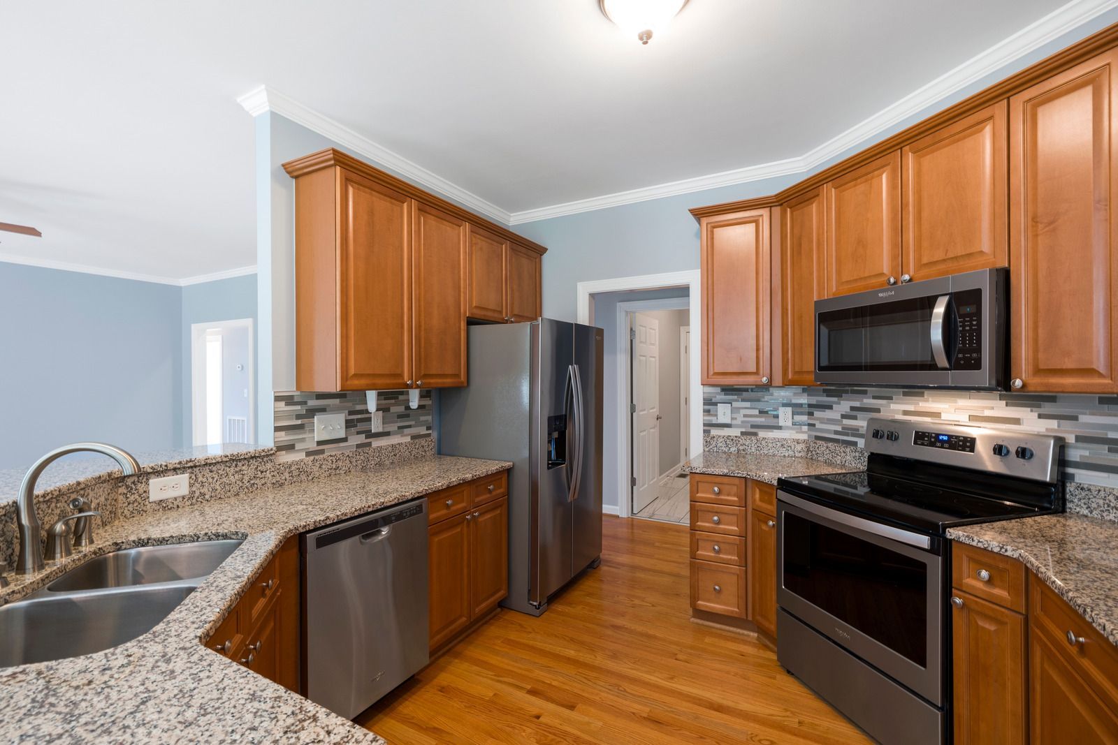 Built-in white shelving and cabinets in a bright room, with tan wood shelves and drop cloths on the floor