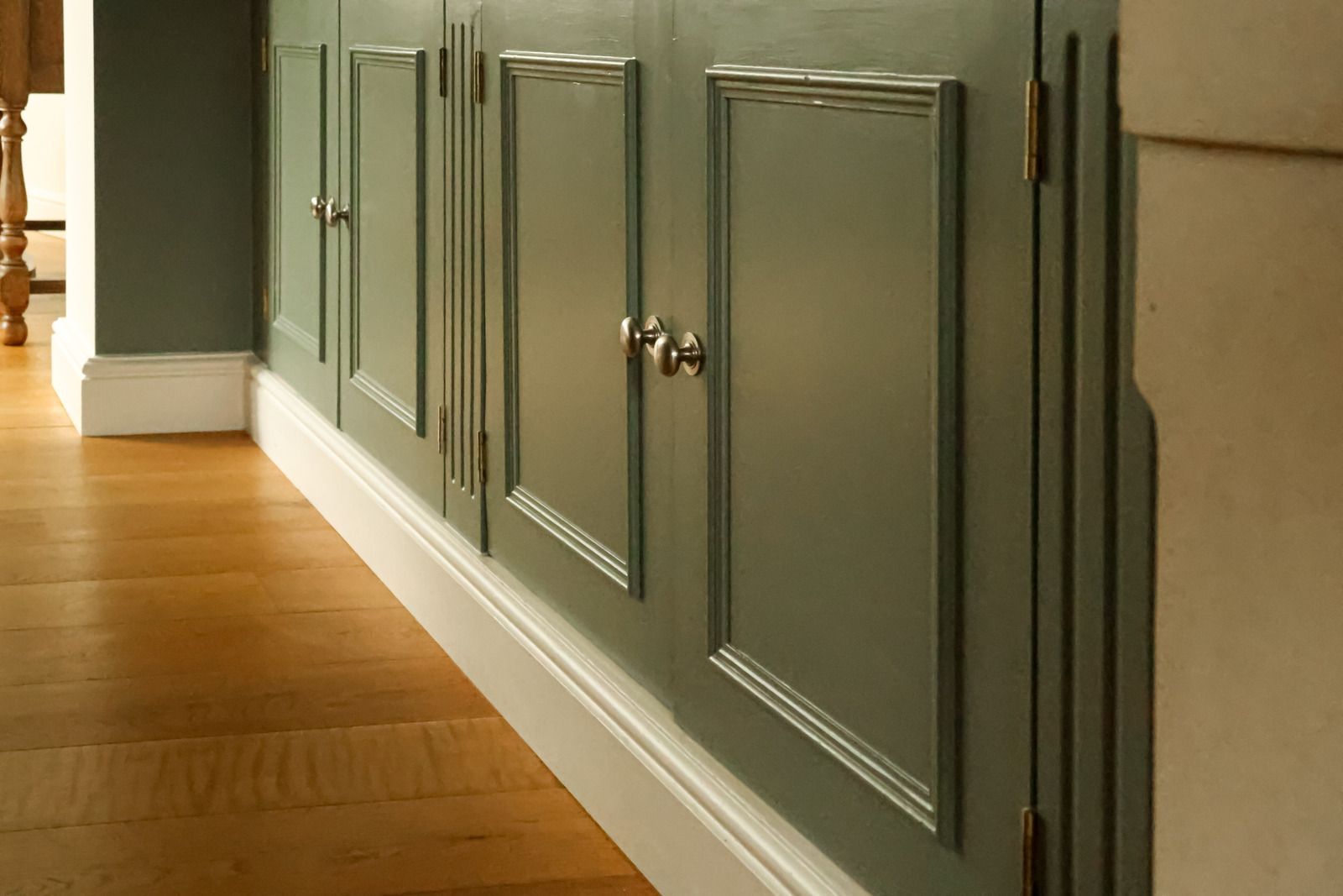 Built-in gray bookcase with cabinets in a bright room beside a window