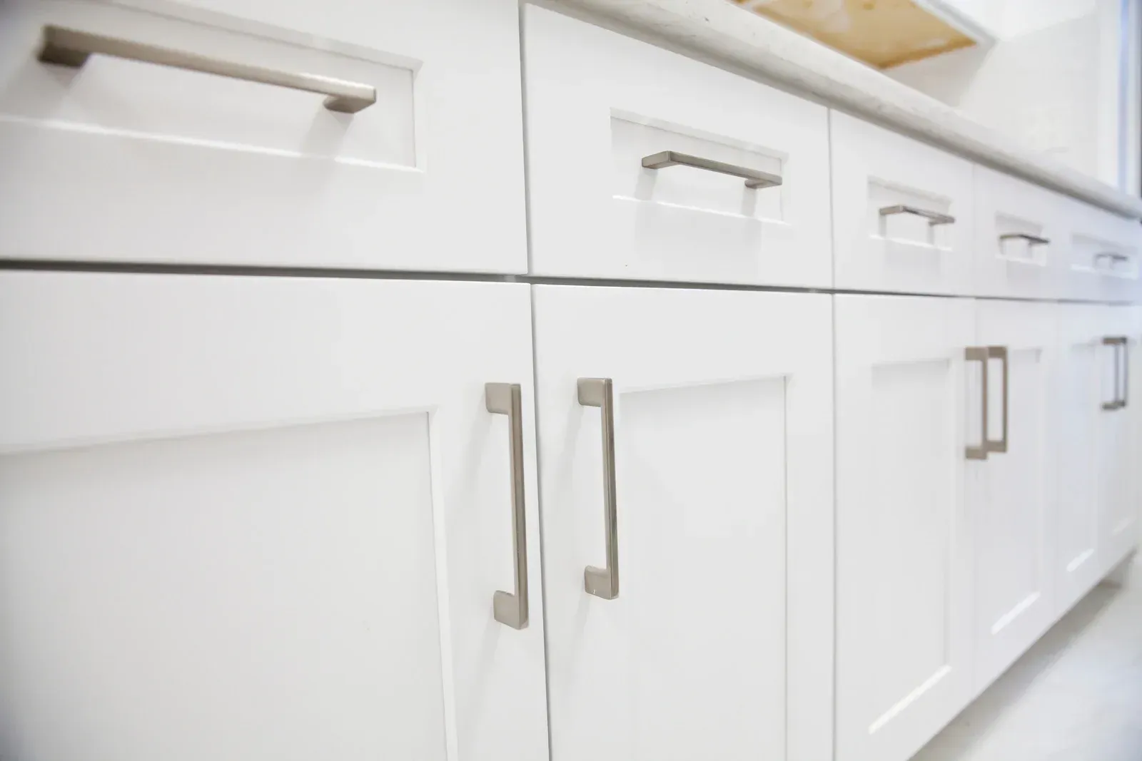 Hand painting a wooden cabinet door teal with a red-handled paint roller