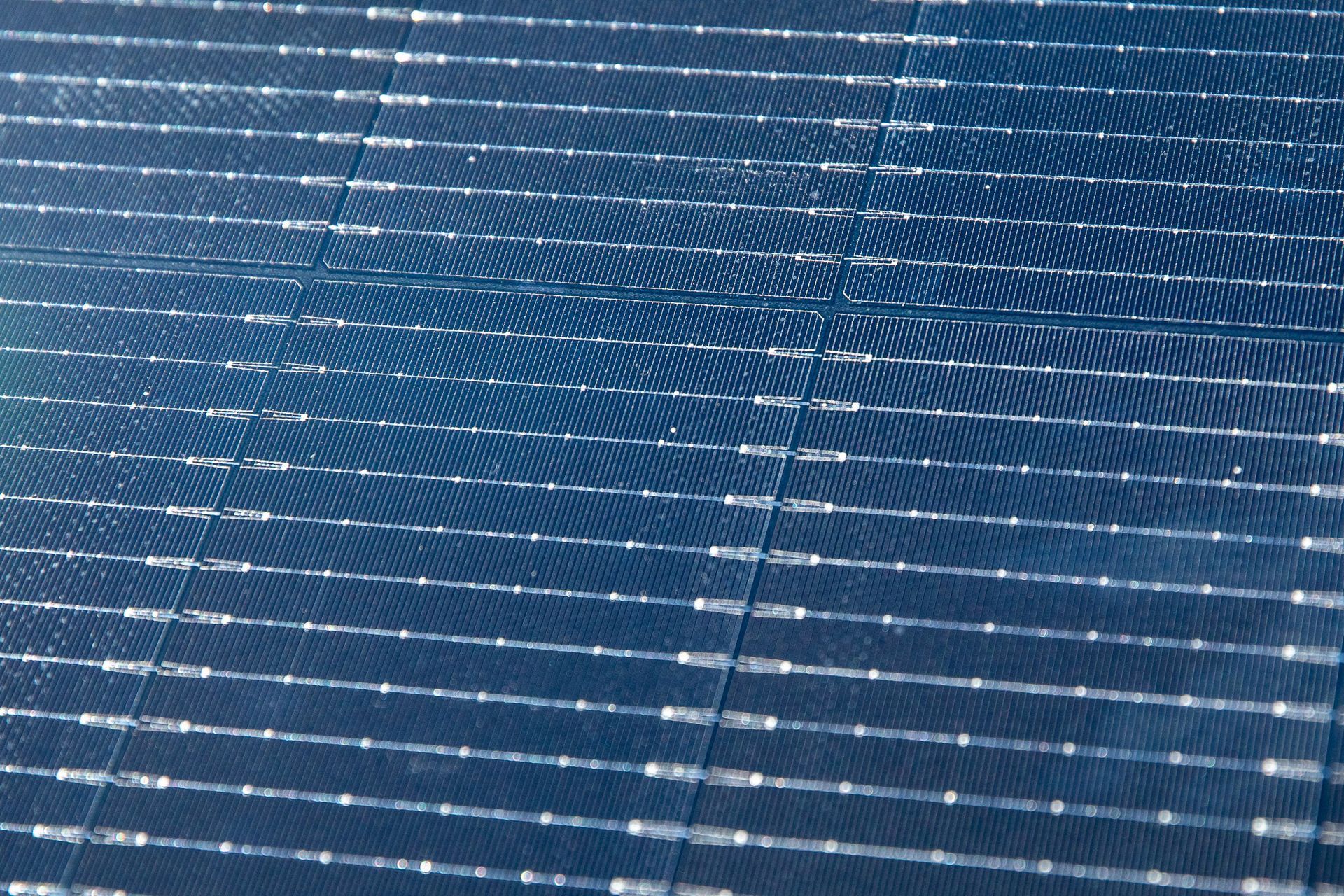 Blue solar panels with rows of white reflections in sunlight