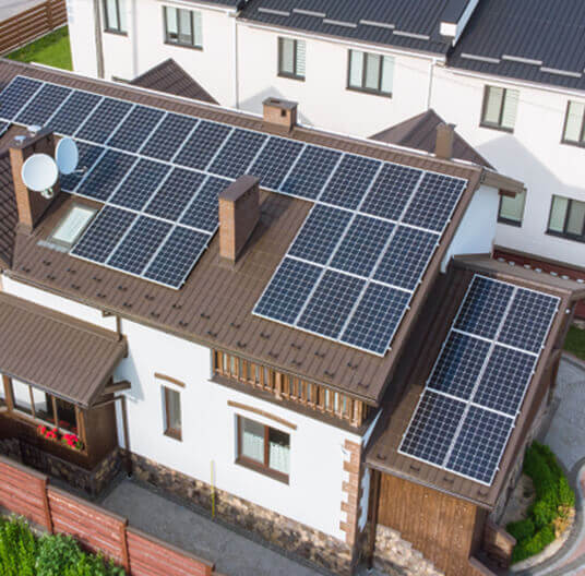 Aerial view of a house roof covered with solar panels and a satellite dish