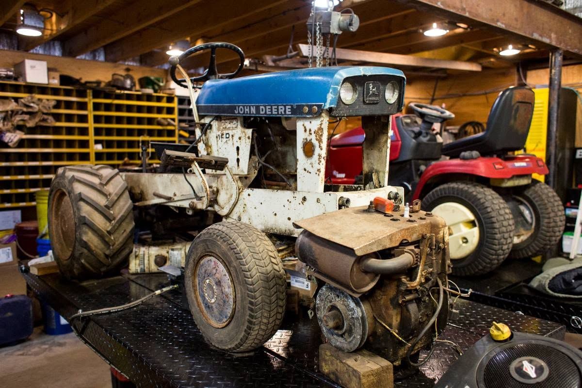 Two old tractors in a garage, one blue and white in the foreground and a red one behind it.