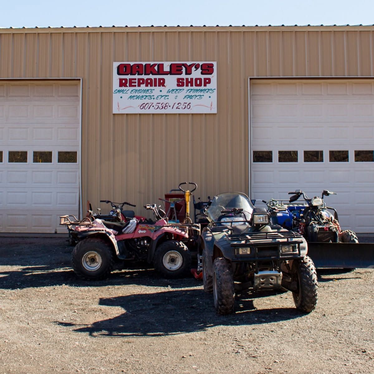 ATVs parked outside Oakley’s Repair Shop on a sunny day