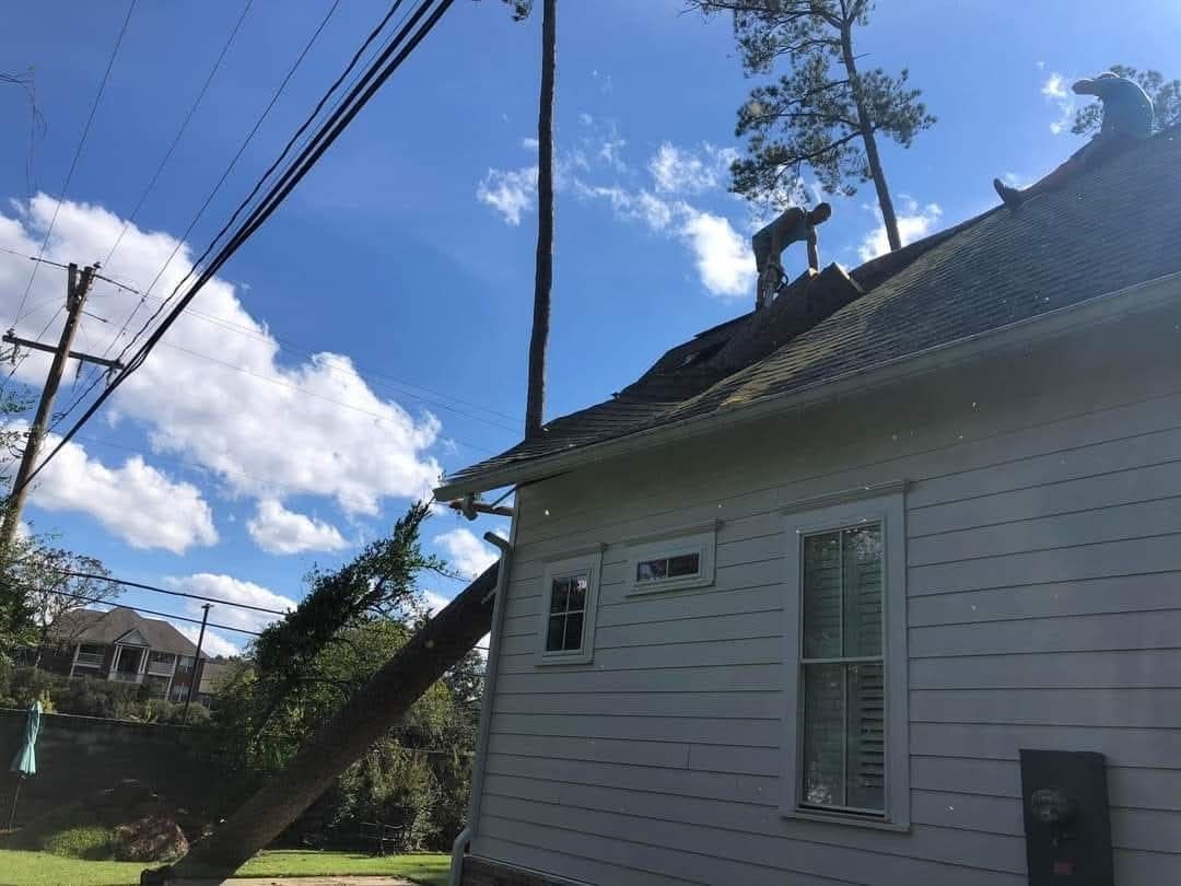 House with a leaning utility pole and overhead wires under a blue sky with clouds