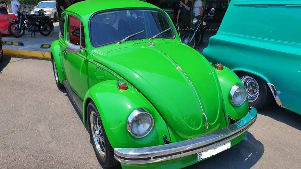 A Green Beetle is Parked Next to a Blue Truck at a Car Show — Endrust (Coffs Harbour) in Coffs Harbour, NSW