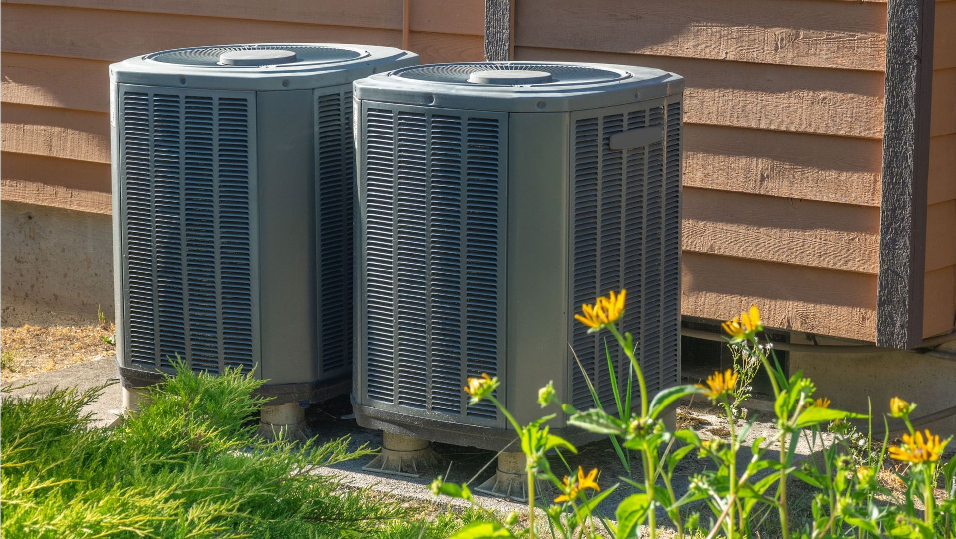 two air conditioners on the side of a house