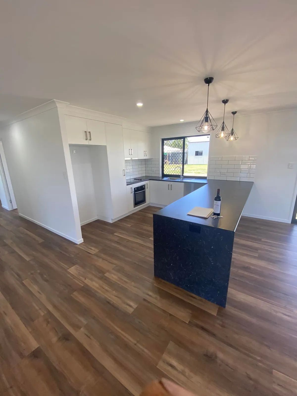 Spacious, Modern Kitchen with A Dark Island, White Cabinets — Country to Coast Homes In Gregory River, QLD