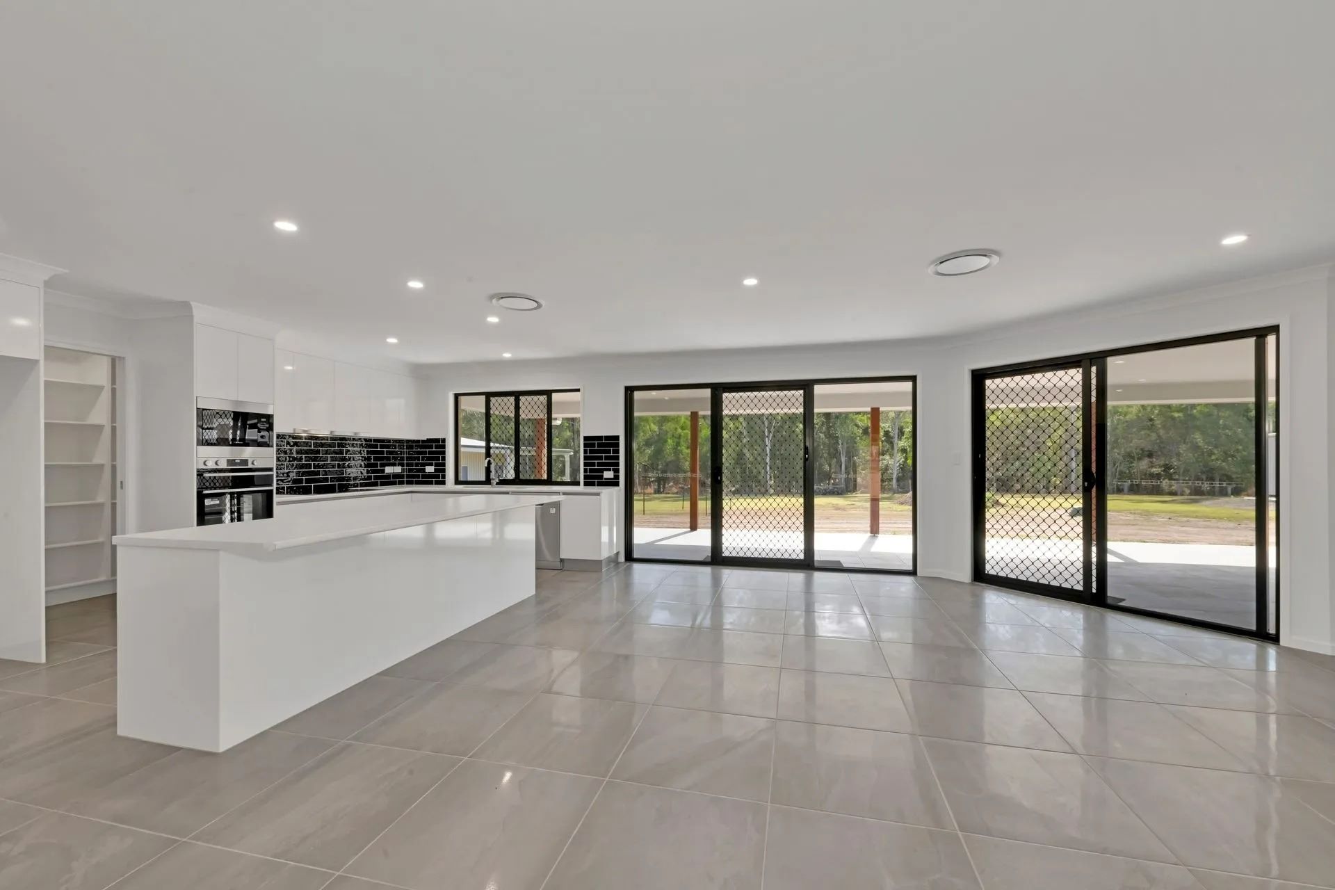 Bright, Open-Plan Kitchen with White Cabinetry and A Large Island — Country to Coast Homes In Gregory River, QLD