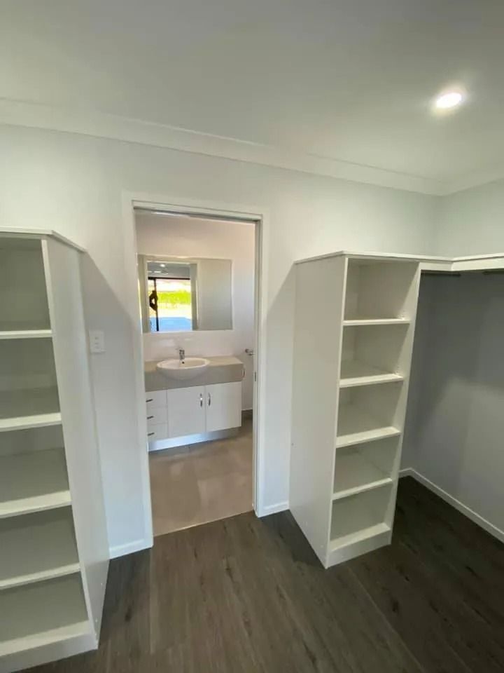 Walk-In Closet with Built-In White Shelving, Leading to A Bathroom — Country to Coast Homes In Gregory River, QLD