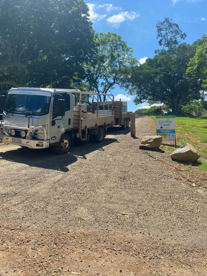 A White Truck Parked on A Gravel Road, Near a Sign and Large Rocks — Country to Coast Homes In Gregory River, QLD