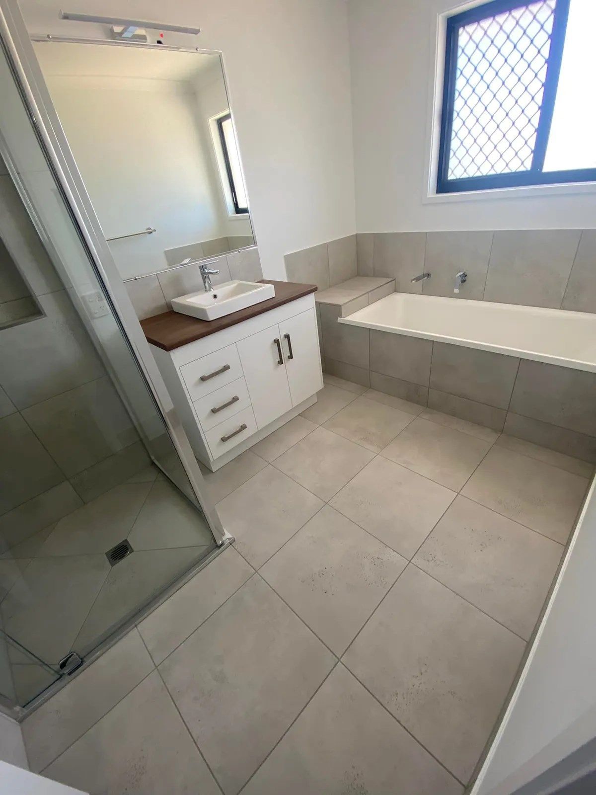 Bathroom with White Vanity, Shower, Bathtub, and Tiled Floor — Country to Coast Homes In Gregory River, QLD