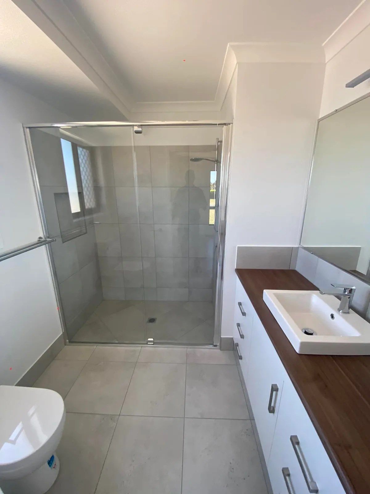 Modern Bathroom with A Glass Shower, White Vanity, and A Toilet — Country to Coast Homes In Gregory River, QLD