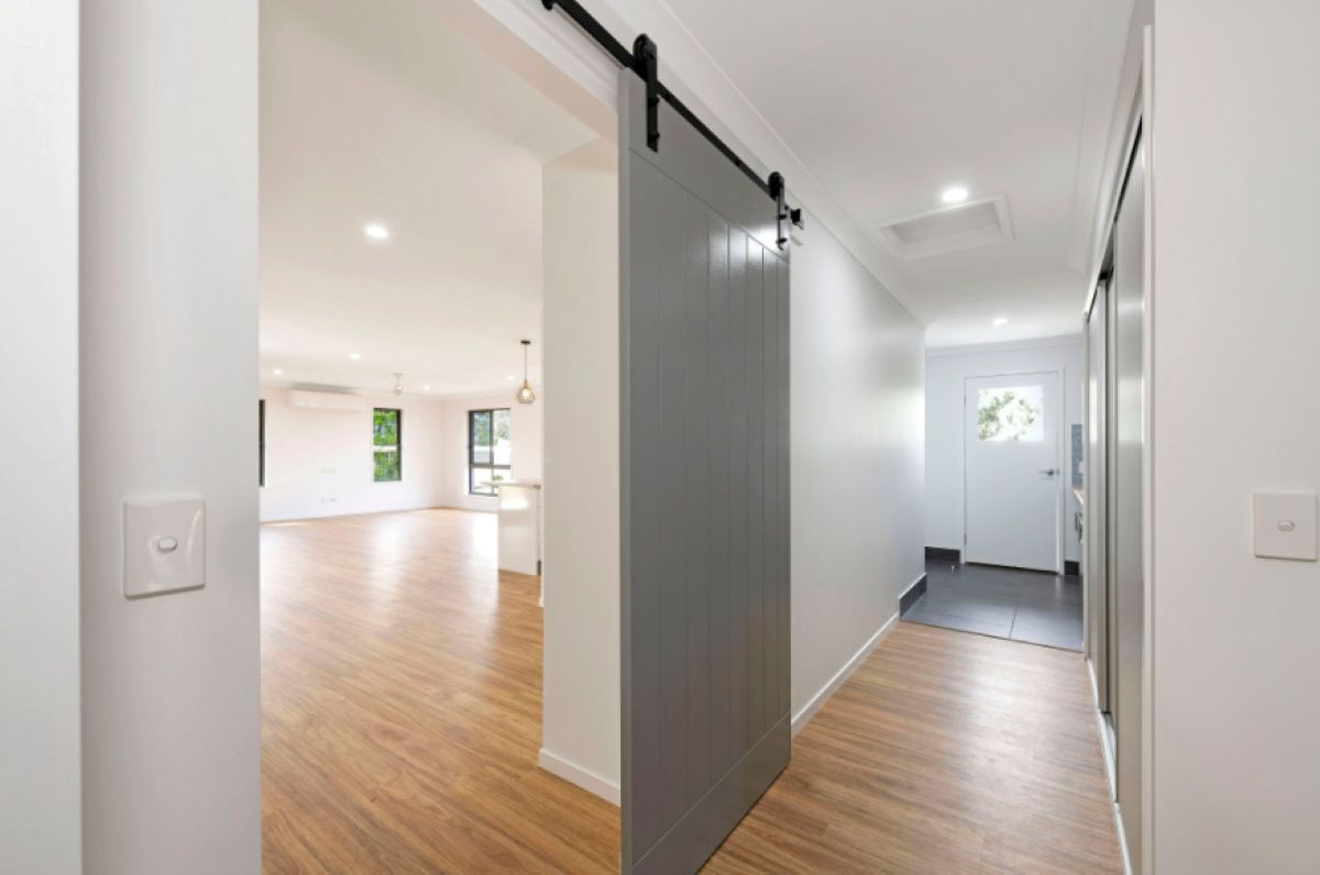 Hallway with Sliding Gray Door and Wooden Floor — Country to Coast Homes In Gregory River, QLD