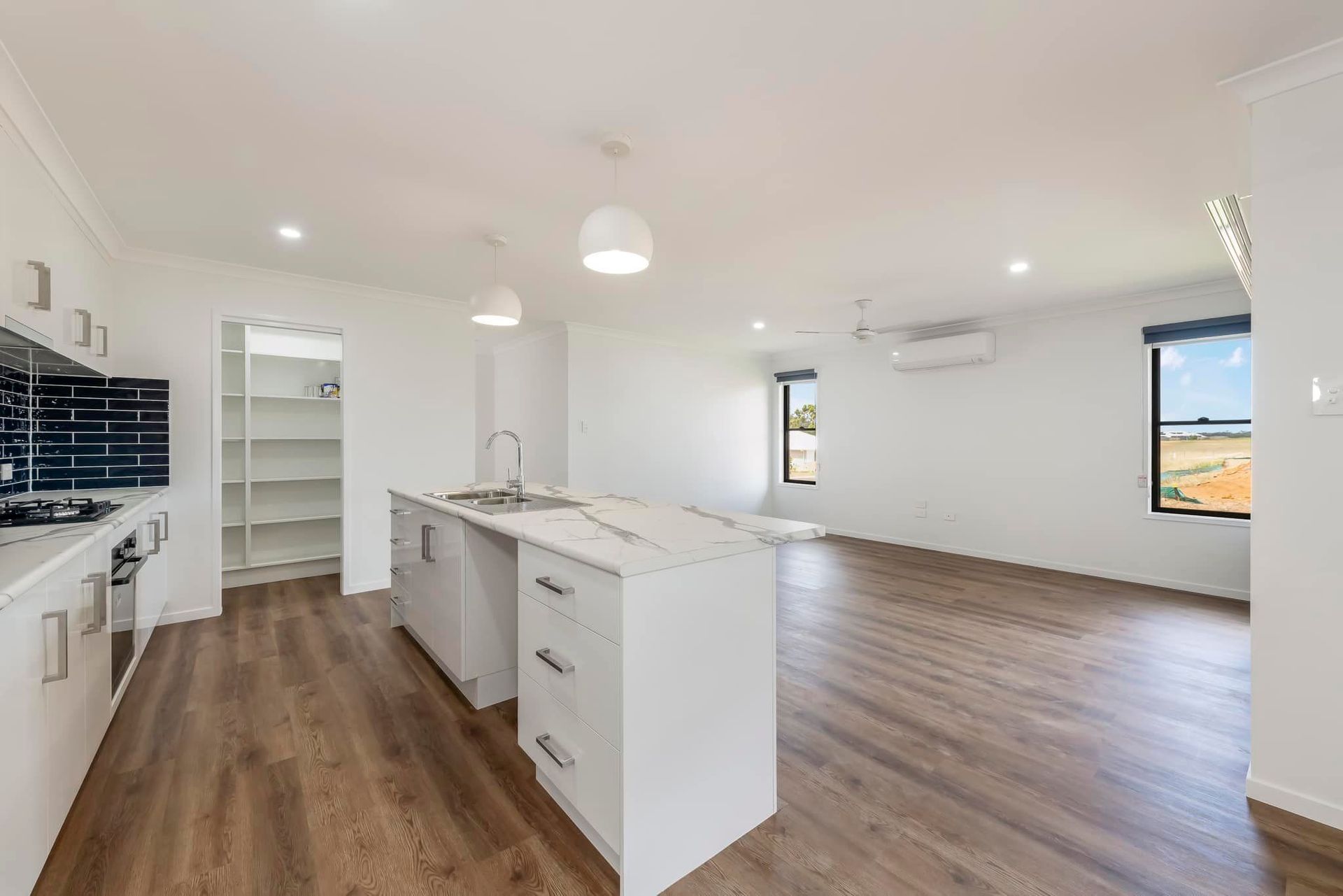 Modern Open-Plan Kitchen and Living Space with White Cabinetry, Island — Country to Coast Homes In Gregory River, QLD