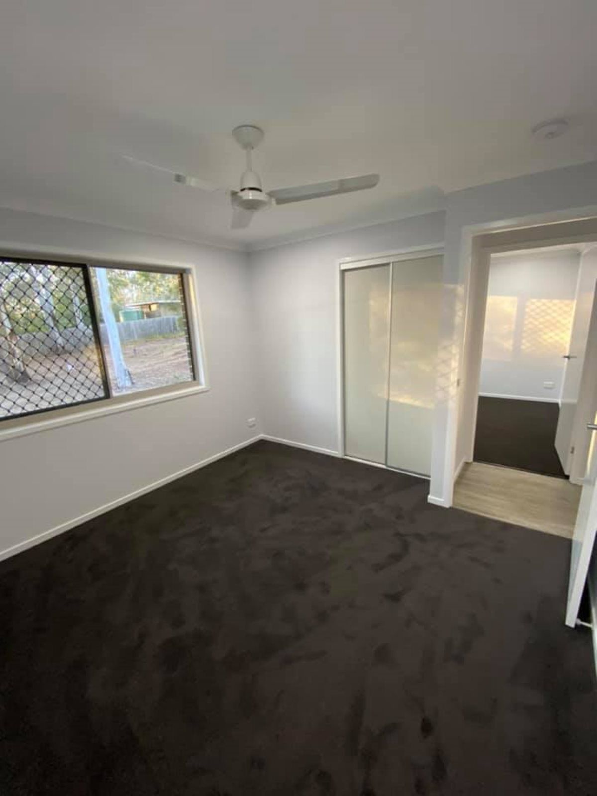 Empty Bedroom with Dark Gray Carpet, a Ceiling Fan — Country to Coast Homes In Woodgate, QLD