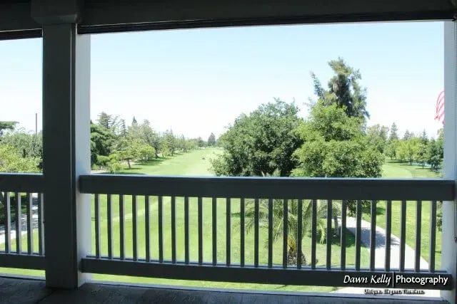 View from a porch railing onto a green golf course under a clear blue sky
