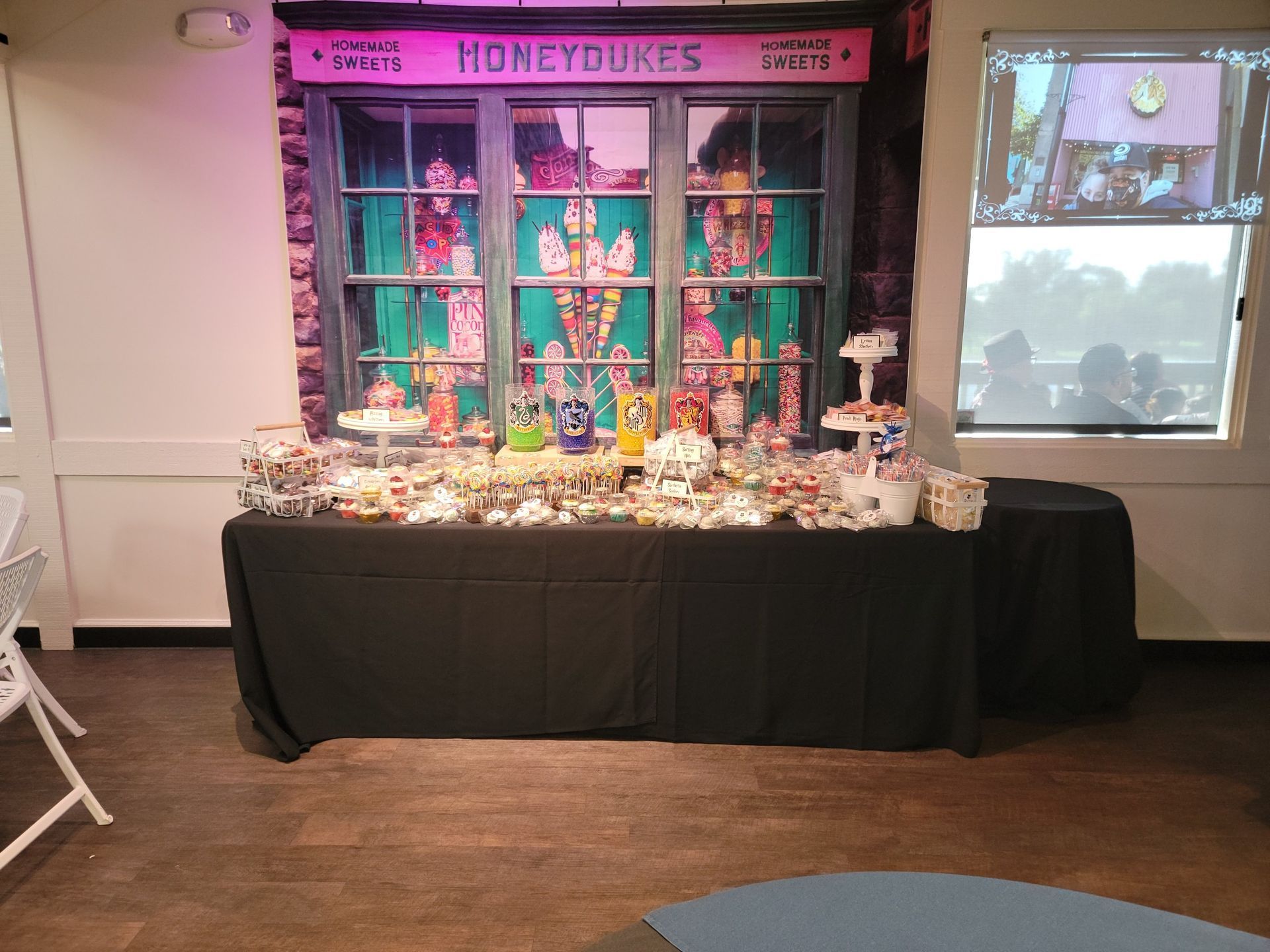 Candy display table in front of a pink storefront backdrop with assorted treats and decorations