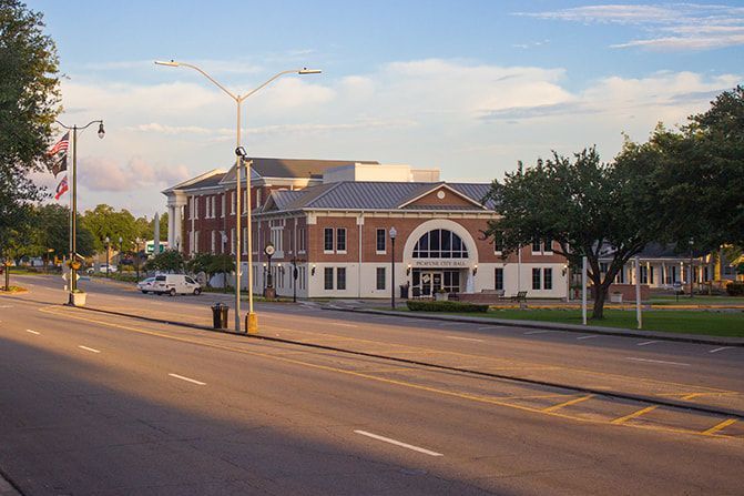 Large brick building with arched entrance and street lights on a wide street.