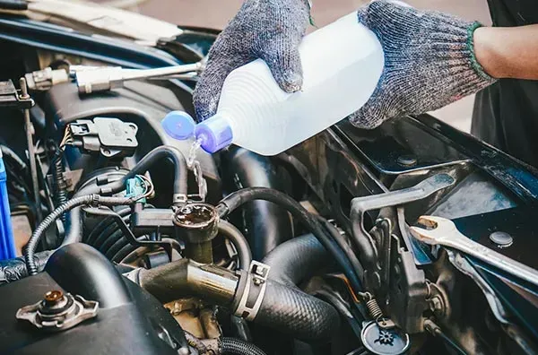 A Person Is Pouring Water Into a Car Engine — Wyong Radiator Repairs in Tuggerah, NSW