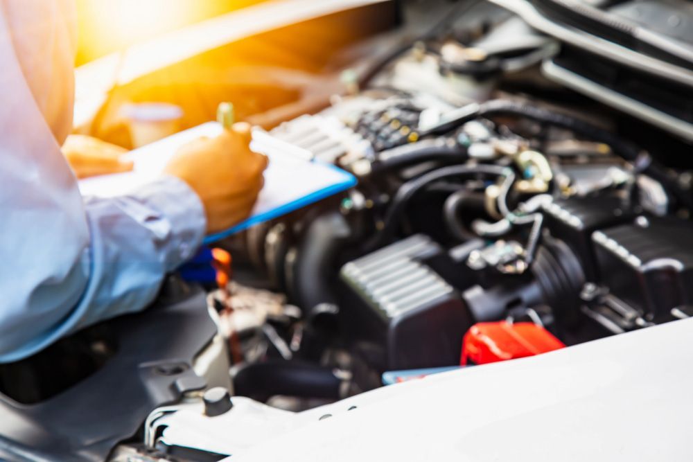 A Mechanic Is Working on The Engine of A Car While Writing on A Clipboard — Wyong Radiator Repairs in Tuggerah, NSW