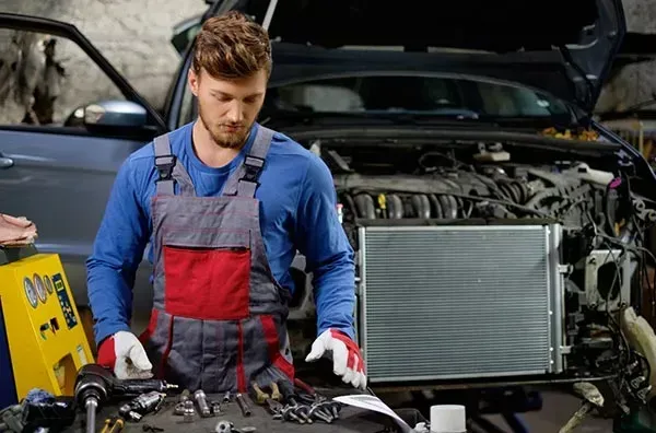 A Man Is Working on The Engine of A Car in A Garage — Wyong Radiator Repairs in Tuggerah, NSW