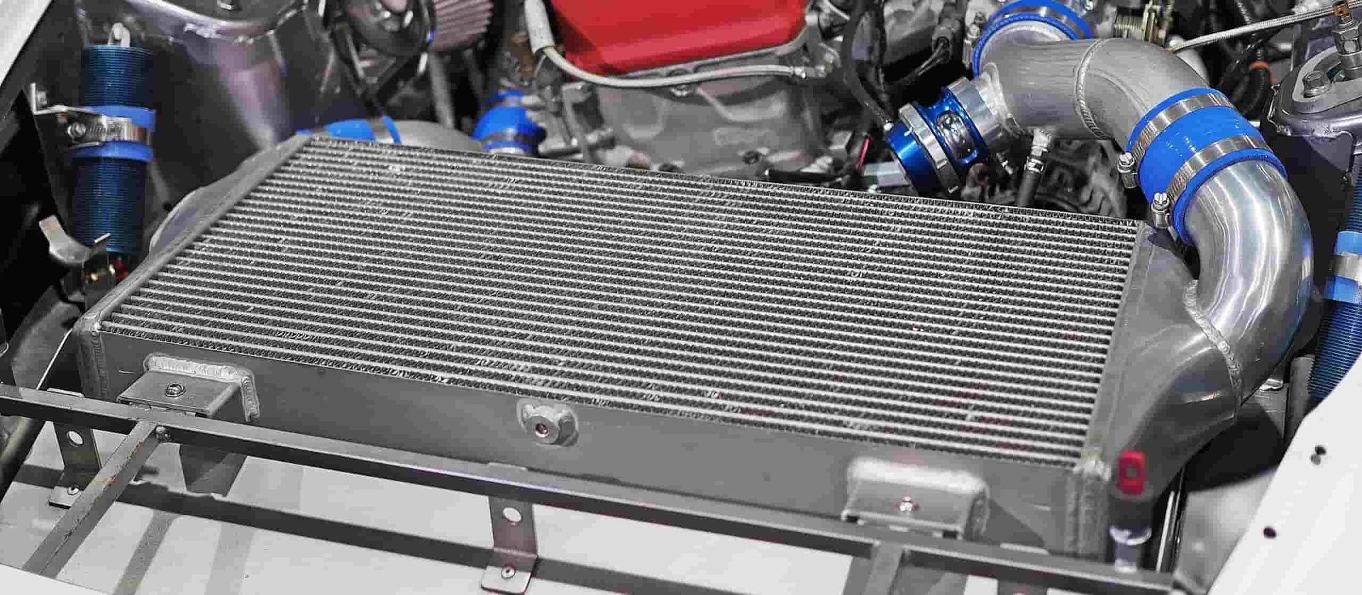 A Close Up of a Car Engine With a Radiator and Blue Hoses — Wyong Radiator Repairs In Terrigal, NSW