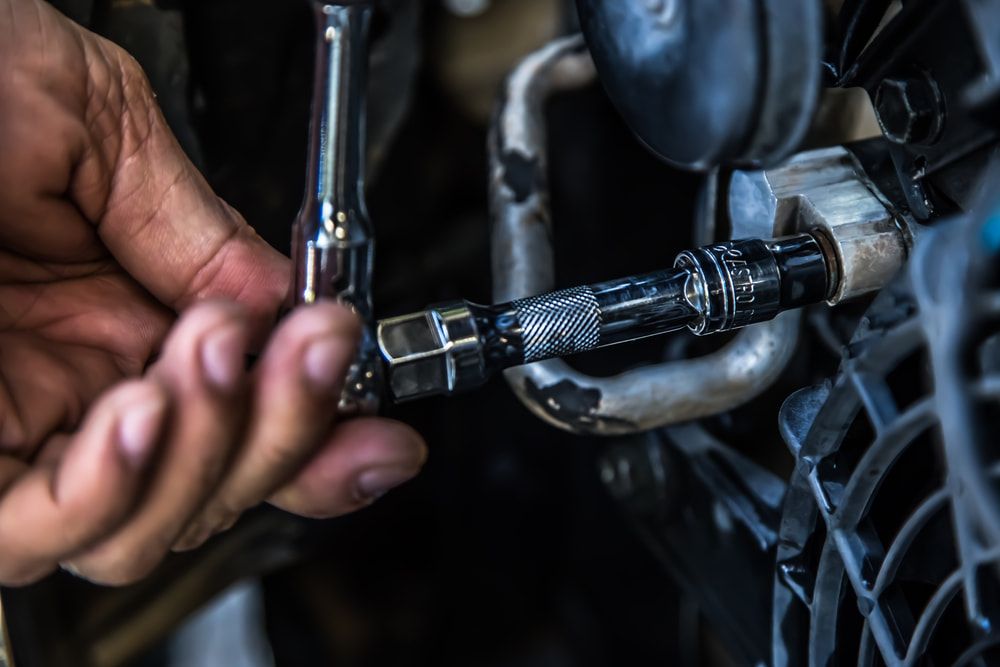 A Person Is Working on A Car with A Wrench and Hose — Wyong Radiator Repairs in Tuggerah, NSW