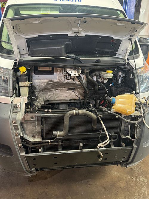 Van with open hood, engine compartment visible. Radiator, hoses, and various components exposed  | S&C Automotive Inc