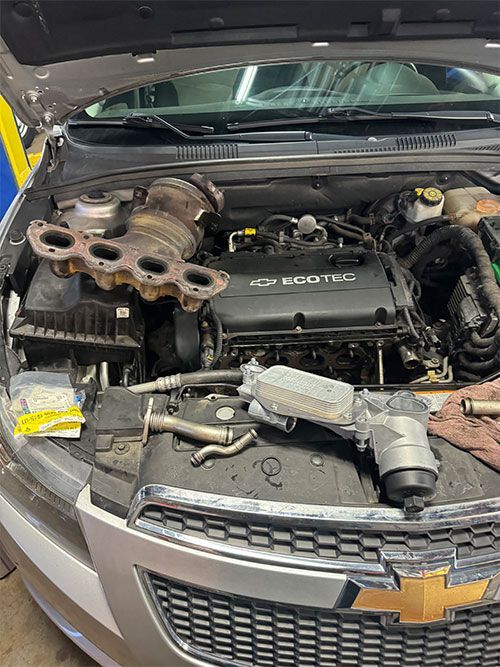 Car engine bay with parts removed for repair; focus on turbocharger and engine components  | S&C Automotive Inc