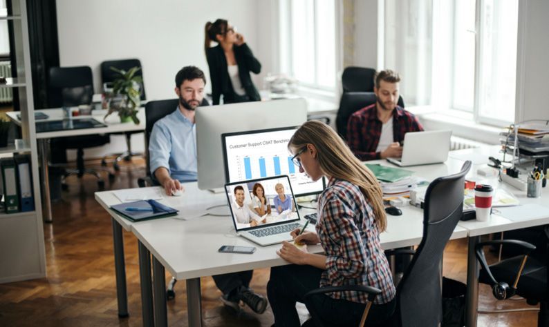 Office team working at desks with laptops and charts in a bright modern workspace